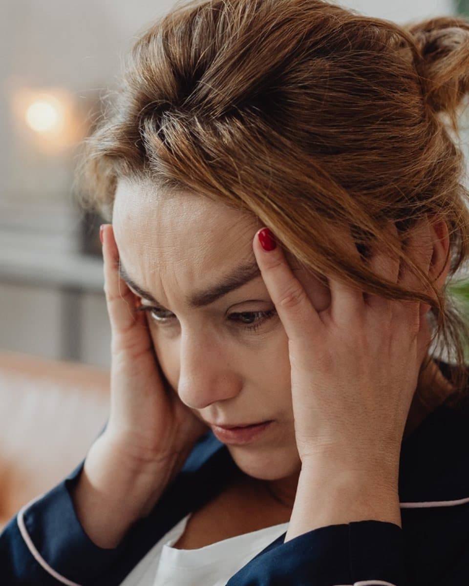 Femme tendue sur son canapé, les mains sur les tempes