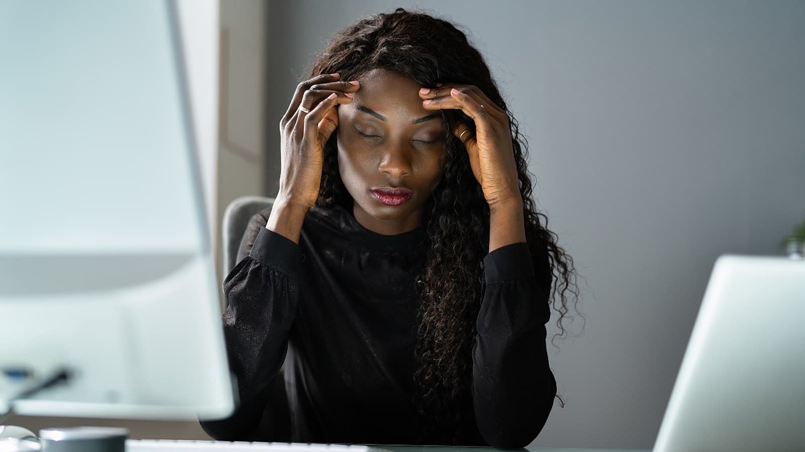Femme stressée devant son ordinateur, se tenant la tête entre les mains