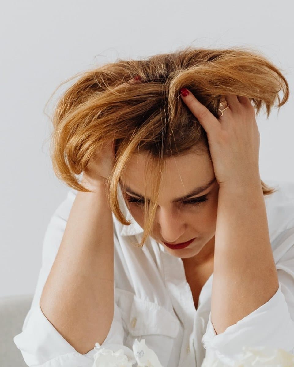 Femme débordée à son bureau, la tête entre les mains devant son ordinateur