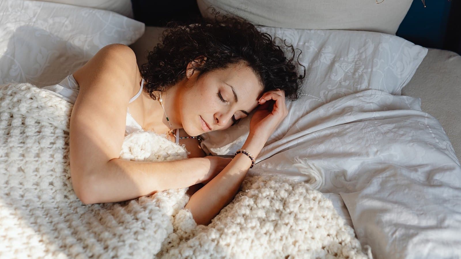 Jeune femme qui dort sereinement dans un lit aux draps blancs