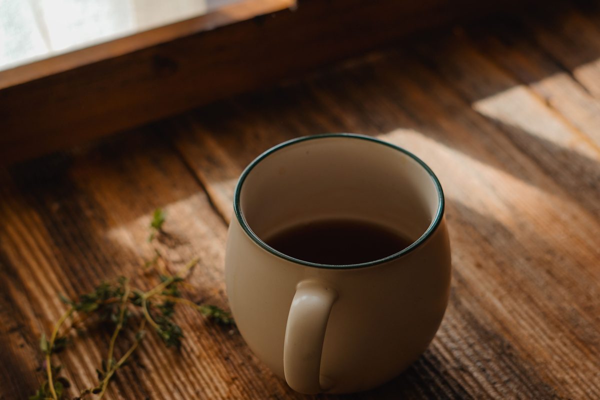 Tasse de café posée sur un rebord de fenêtre en bois, dans la lumière douce du matin